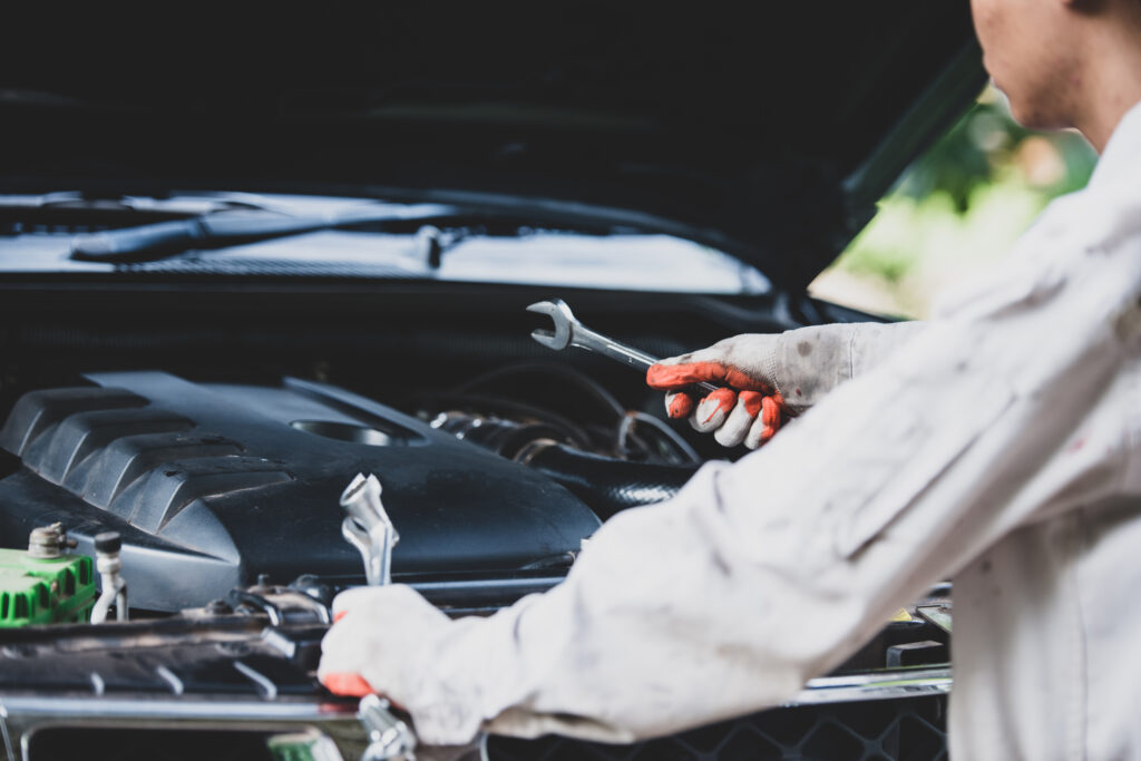 car repairman wearing a white uniform standing and holding a wre